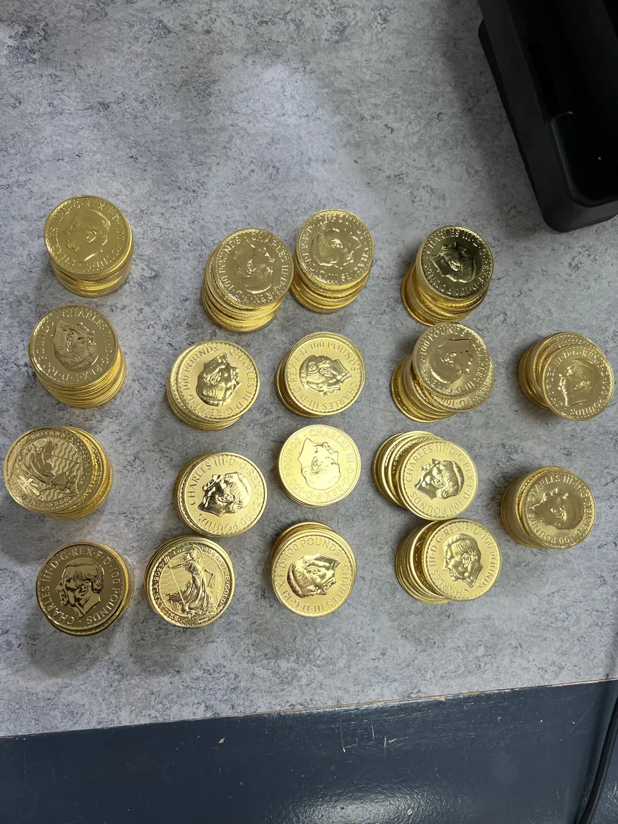 A substantial collection of gold bullion coins stacked in protective capsules