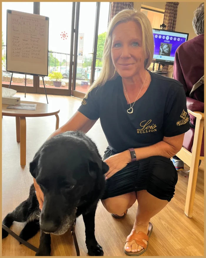 Amy Jackson kneeling beside a black therapy dog at Birmingham Hospice