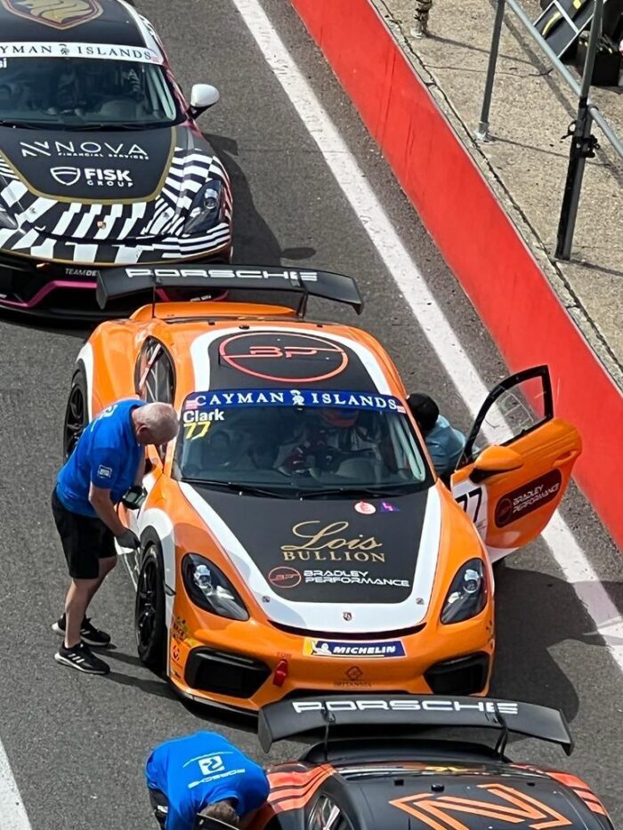 Charles Clark's orange Porsche race car displaying Lois Bullion branding