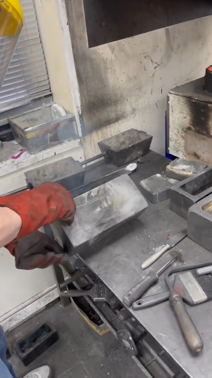 Flipping the mould to release the cooled gold bar onto the table