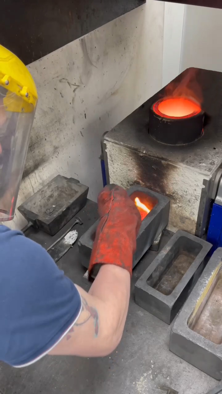 Scraping off black residue from the surface of the gold bar